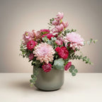 AMABILE FLOWER SHOP pink and red mixed flower arrangement with eucalyptus in a grey vase.
