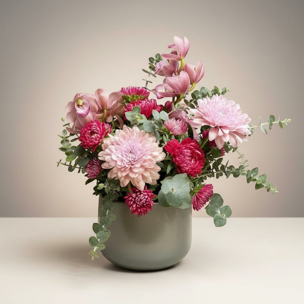 AMABILE FLOWER SHOP pink and red mixed flower arrangement with eucalyptus in a grey vase.